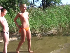 Topless teens in bikini bottoms playing at the lake