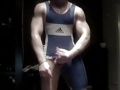 Muscled wrestler stroking big uncut cock in singlet