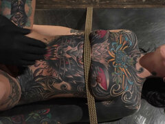 Tattooed girl is bound and fingered in BDSM dungeon