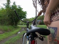Biker girl with a butt plug rides her bike on the street, catching the attention of a horny driver