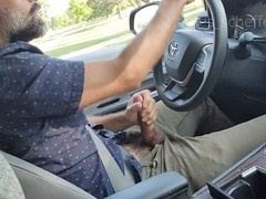 Driving hunk strokes his massive cock in the car