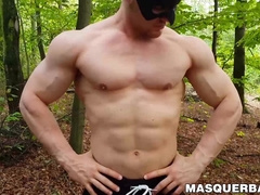 Muscular dude strokes his cock outdoors while wearing a mask