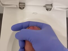 Doctor is jerking off with latex gloves at a toilet in Hospital