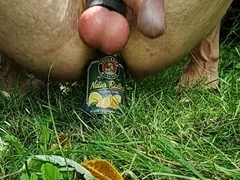 Drilling rump with a bottle outdoors and jizm with strapped sack