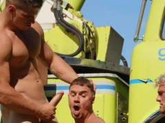 Hunks are having a threesome next to the big vehicle