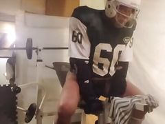 Football guy in jock strap lifts weights